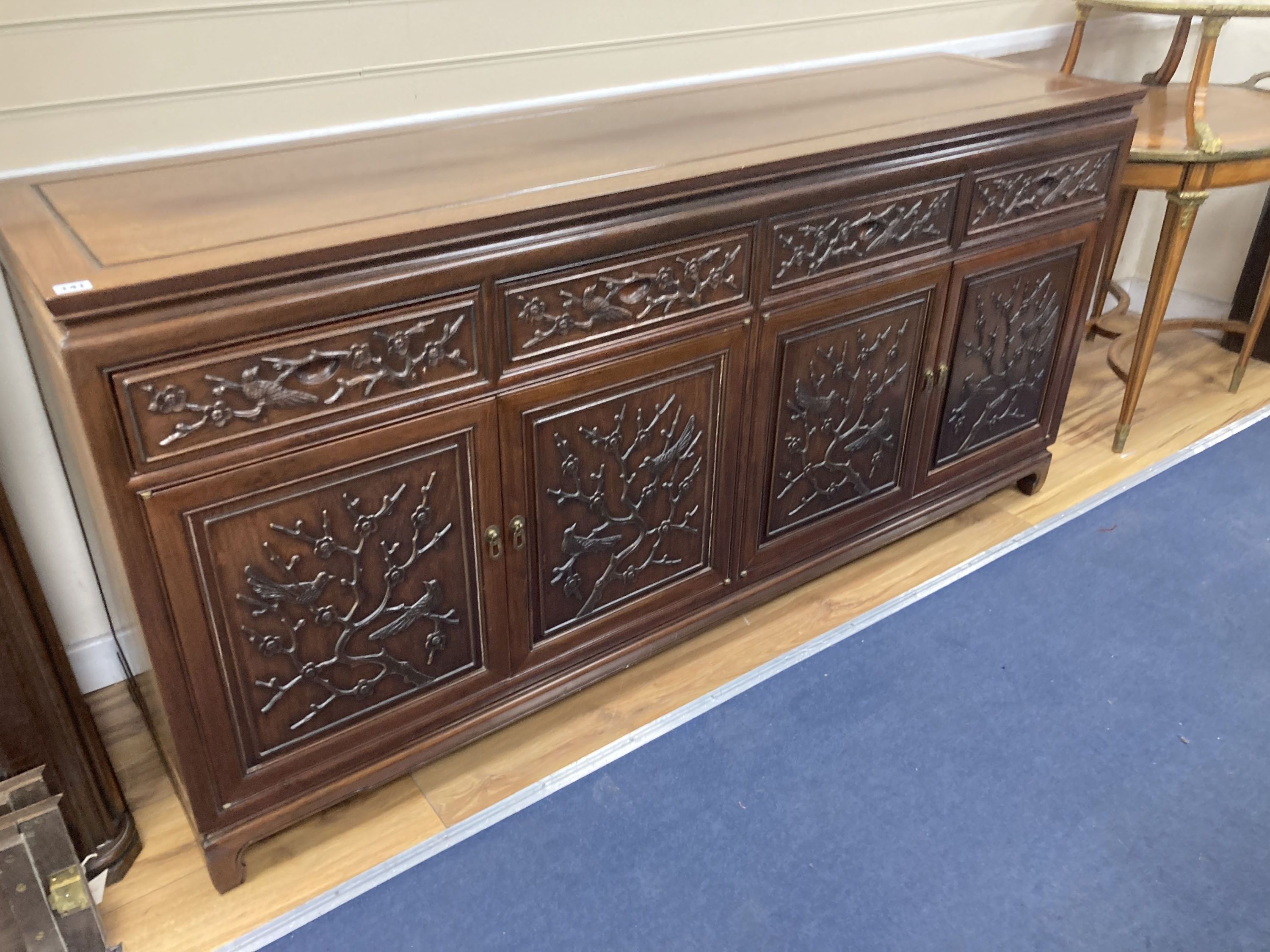 A 20th century Chinese carved hardwood dining room suite comprising sideboard fitted with four drawers above four carved panelled cupboard doors, shelved interior, raised on bracket base, length 183cm, depth 48cm height